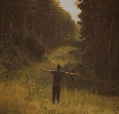 a man standing in the middle of a forest holding his arms out