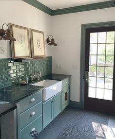 a kitchen with green cabinets and black counter tops next to a double doored doorway