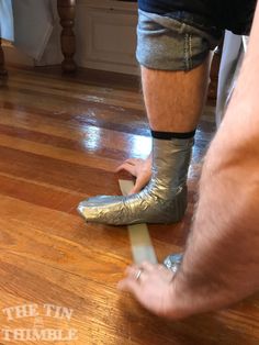 a man wearing silver shoes standing on top of a hard wood floor