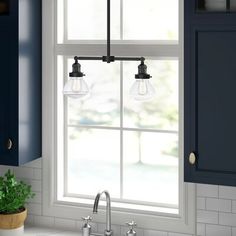 a kitchen with blue cabinets and a white sink under a hanging light over the window