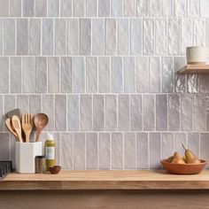 a kitchen counter with wooden utensils on top of it and a white tiled wall behind it