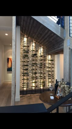 a room filled with lots of bottles of wine on top of a wooden floor next to a stair case