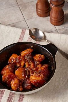 a pan filled with food sitting on top of a table next to a wooden spoon