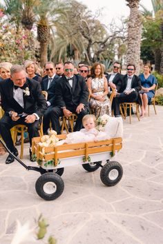 a baby in a wagon being pulled by a man and woman at a wedding ceremony