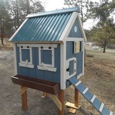 a blue and white birdhouse sitting on top of a wooden platform