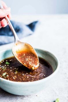 a spoon is being used to stir sauce in a bowl