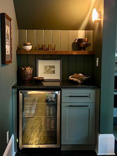 an empty refrigerator in a small kitchen next to a wall with pictures on the shelves