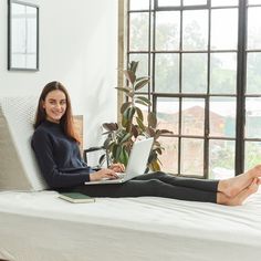 a woman sitting on a bed with her legs crossed and laptop in front of her