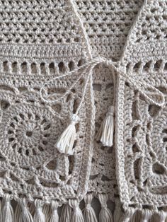 the crocheted tablecloth has tassels on it and is made from white yarn