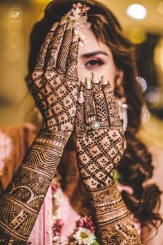 a woman holding her hands up to her face with henna on top of her