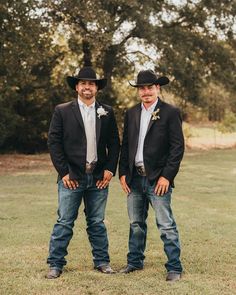 two men in cowboy hats standing next to each other on a field with trees behind them