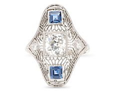 This Art Deco-period ring features not one, but two exceptionally rare Yogo sapphires. First discovered in the late 19th century in the Yogo Gulch in Montana, Yogo sapphires are considered among the world’s finest prized gemstones. These examples total approximately 0.75 carat and are joined by 1.10 total carats of white diamonds in their classic platinum Art Deco setting. Art Deco Sapphire Diamond Ring In Platinum, Art Deco Platinum Sapphire Ring, Collectible Art Deco Sapphire Ring, Art Deco Platinum Sapphire Ring With 17 Jewels, Blue Art Deco Diamond Ring With Diamond Cut, Antique Sapphire Ring In Platinum, Antique Blue Sapphire Ring In Platinum, Antique Oval Sapphire Ring In Platinum, Collectible Art Deco Platinum Sapphire Ring