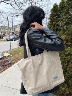 a woman is standing on the sidewalk with her back to the camera and holding onto a bag