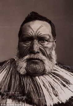 an old photo of a man with face paint and feathers on his head, looking at the camera