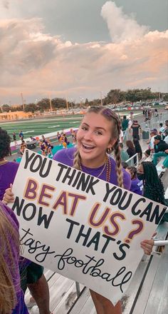 a woman holding a sign that says you think you can beat us now that's easy football