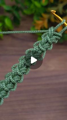 a green crochet piece with a white triangle on it hanging from a hook