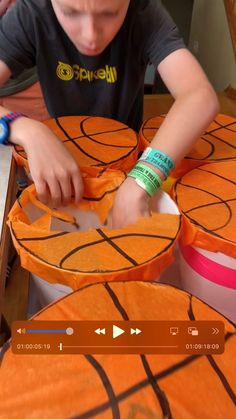 a young boy is cutting out some paper basketballs