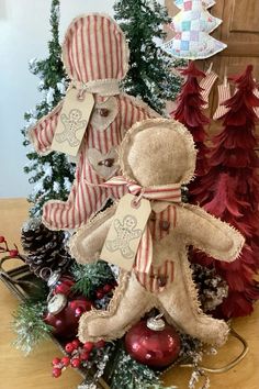 two teddy bears sitting next to each other on top of a wooden table in front of christmas trees