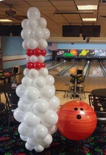 bowling alley decorated with white and red balloons, bowling pins and bowling balls in the background