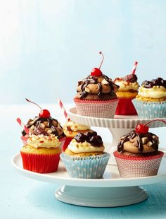 cupcakes with chocolate and cherries on top are arranged on a cake platter