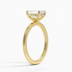 a yellow gold engagement ring with an oval cut diamond on the center and side stones