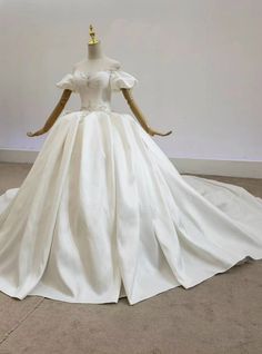 a white wedding dress on display in front of a wall with a crown on it