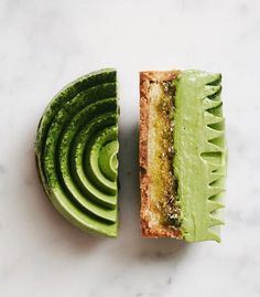 an avocado sandwich cut in half on top of a white countertop next to a slice of avocado