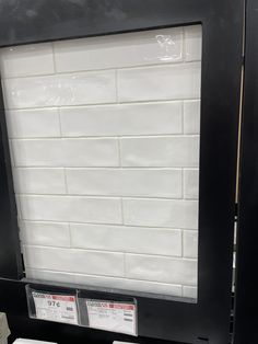 a white brick wall mounted to the side of a black framed display case in a store