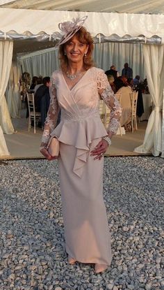 a woman wearing a dress and hat standing in gravel