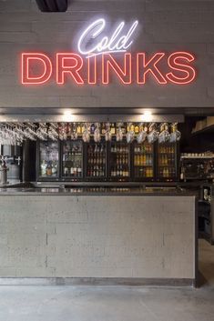 the neon sign above the bar says cold drinks and is lit up with red lights