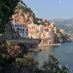 an old bridge crossing over the water in front of some buildings on top of a hill