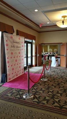 a carpeted room with red rope barriers and pink rugs on the floor in front of an entrance