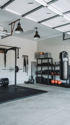 an empty garage with gym equipment and punching bags on the floor in front of it