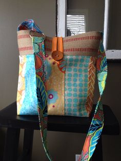 a colorful bag sitting on top of a wooden chair next to a window with a pair of scissors in it