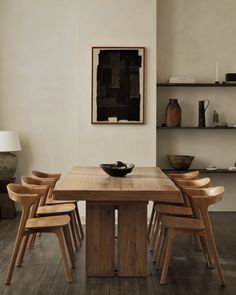 a wooden table surrounded by chairs in a room