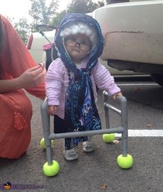 a small child in a walker with tennis balls on the ground next to a woman