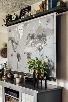 a large map is hanging on the wall above a dresser in a room with bookshelves