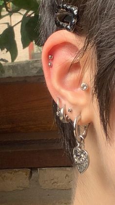 a close up of a person's ear with some piercings on top of it