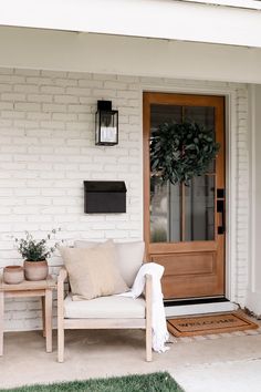 a white couch sitting on top of a porch next to a wooden table and potted plant