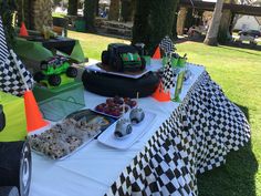 a table topped with lots of food on top of a grass covered field next to trees