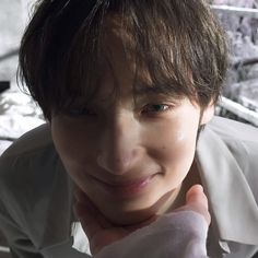 a close up of a person wearing a white shirt and tie with his hand on his chin