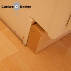 the corner of a room with wood flooring next to an open door that says cucko 4 design