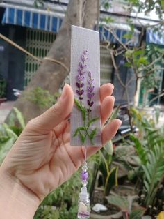 a hand holding up a piece of fabric with flowers on it and beads hanging from the end