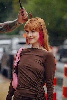 a woman with red hair holding an umbrella