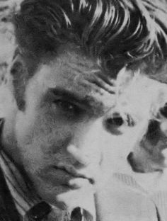 a black and white photo of a young man with his hand on his chin looking at the camera