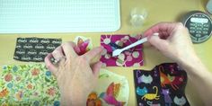 a person is cutting paper with scissors on a table next to other crafting supplies