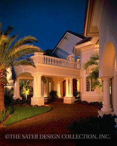 a large white house with palm trees in the front yard at night, lit up by street lights