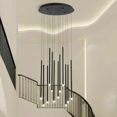 a modern chandelier hanging from the ceiling in a room with white walls and stairs