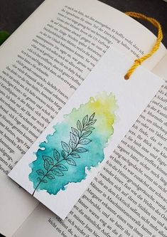 an open book with a watercolor painting on the cover and a string attached to it