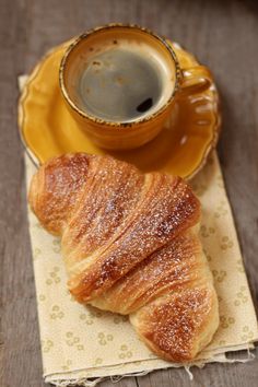 two croissants on a napkin next to a cup of coffee